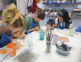 Grupo concentrado mientras pinta su azulejo