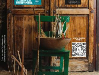 Al fondo una puerta de madera y al frente de la imagen una silla verde con distintos materiales de artesanía tradicional canaria.