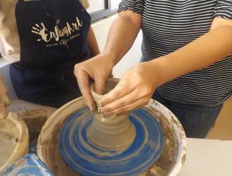 Imagen de torno alfarero con las manos de una persona modelando una pieza de arcilla