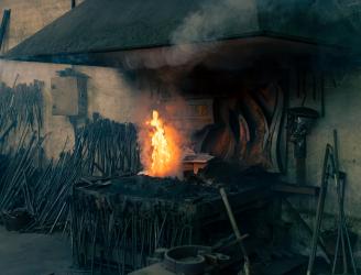 imagen de la fragua del taller de Tofé forja artística en la que destaca la llama del fuego en contraste con el negro del carbón. Fotografía de Jonatan Narro