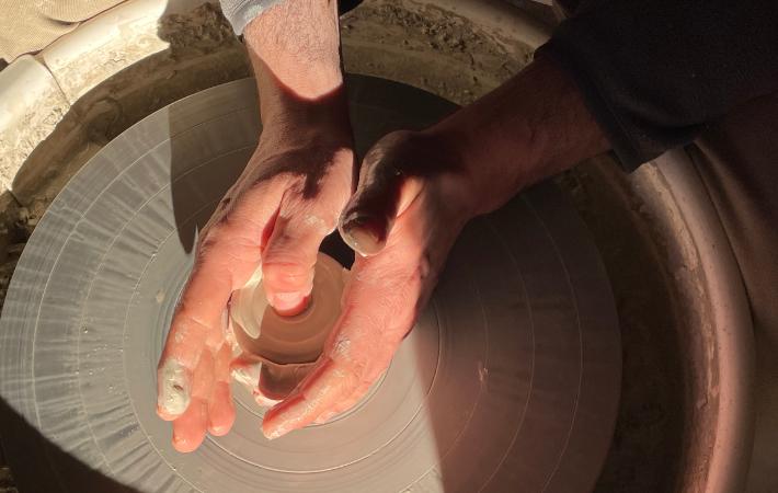 Manos trabajando en el torno de alfarería