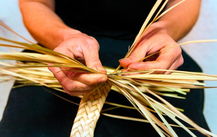 Manos de mujer haciendo pleita de palmito.