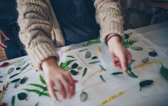 Estampación botánica, manos colocando hojas sobre el tejido.