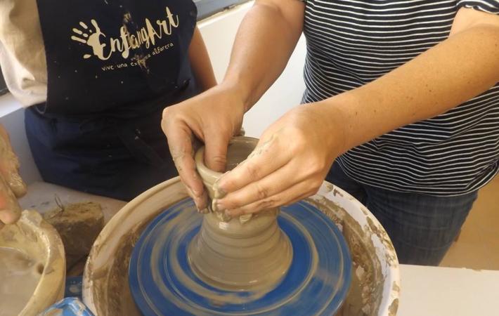 Imagen de torno alfarero con las manos de una persona modelando una pieza de arcilla