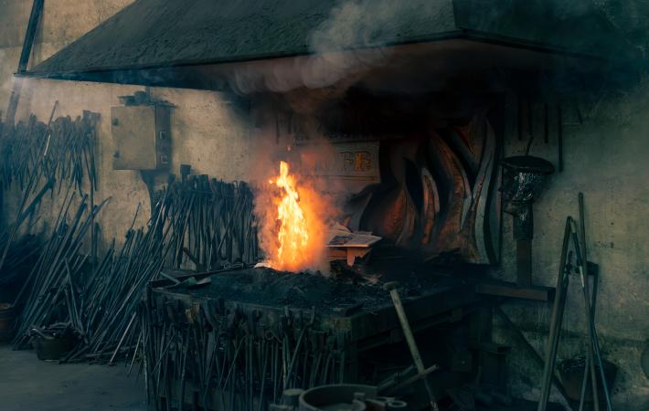 imagen de la fragua del taller de Tofé forja artística en la que destaca la llama del fuego en contraste con el negro del carbón. Fotografía de Jonatan Narro