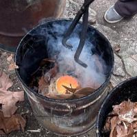 Introduciendo las piezas en los cubos metálicos con hojas secas y serrín