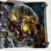 Obra realizada en vidrio de 4mm montada sobre una composición. Esmaltada con polvo de vidrio en superficie y terminada en frío con acrílicos dorados y espejada.