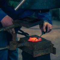 foto detalle de las manos trabajando con una lamina de metal candente para la elaboración de una hoja de parra. Fotografía de Jonatan Narro