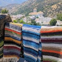 Jarapas de La Alpujarra de varios colores y al fondo Bubión